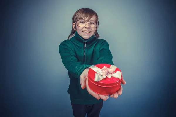 European-looking boy of ten years  in glasses holding  a gift bo — Stock Photo, Image
