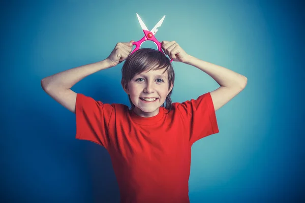 European-looking boy of twelve  scissors in  hand, mouth open on — Stock Photo, Image