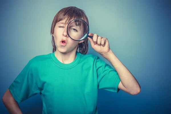 European-looking boy  of ten  years holding a magnifying glass, — Stock Photo, Image