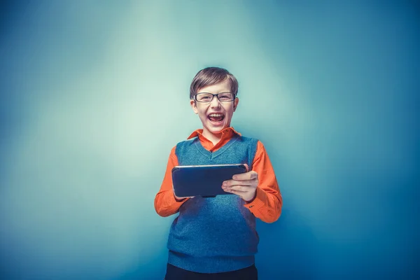 European -looking  boy of ten years in glasses holding tablet in — Stock Photo, Image