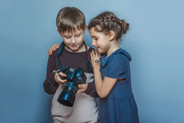 Ragazzo adolescente con una ragazza che guarda le immagini sulla macchina fotografica su un gra — Foto Stock