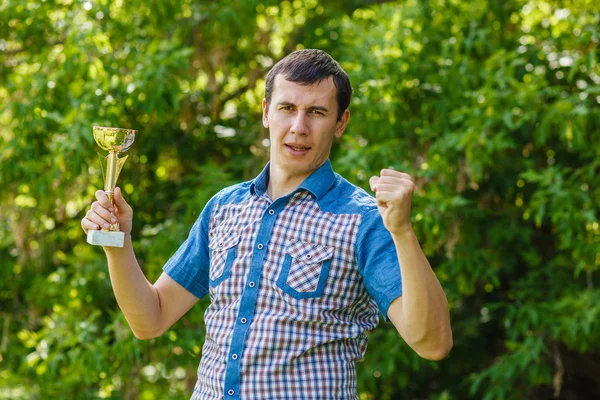Man holding a sports cup on the street victory against the  gree — Stock Photo, Image