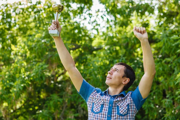 Man holding a sports cup on the street victory against the green — Stock Photo, Image