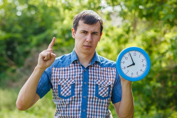 Uomo tenendo orologio mostrando pollici su uno sfondo verde summe — Foto Stock