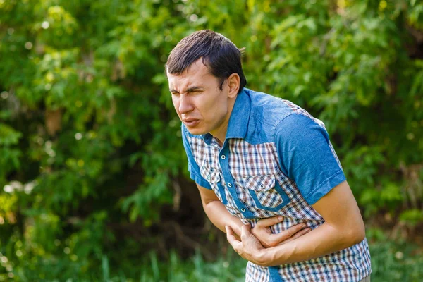 Adam sokakta karın ağrısı yeşil bir arka plan üzerinde s yaprakları