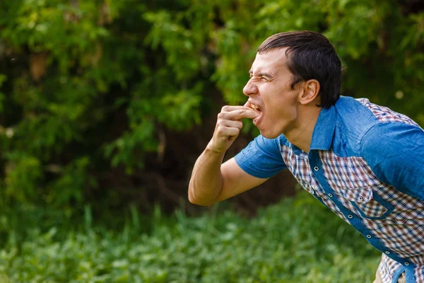 Uomo sulla strada nausea vomito su uno sfondo verde foglie — Foto Stock