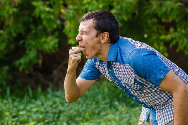 Man on the street nausea vomiting on a green background leaves s — Stock Photo, Image