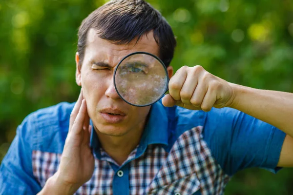 The man in the street holding a magnifying glass big eyes on a g — Stock Photo, Image
