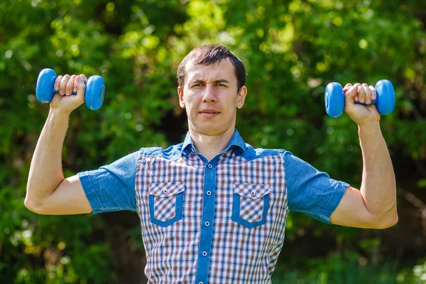 L'uomo per strada che tiene in mano un manubrio di plastica sport su un blu — Foto Stock