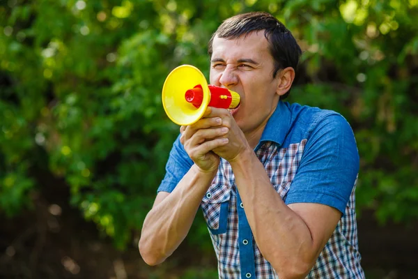 L'uomo per strada che tiene un altoparlante di plastica grida sul verde — Foto Stock