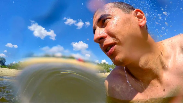 Hombre desnudo sonriendo en las gotas de agua salpicando verano contra —  Fotos de Stock