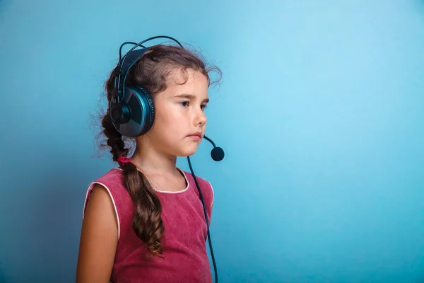 Teen dziewczyna dziecko w słuchawki z mikrofonem na niebieskim tle — Zdjęcie stockowe