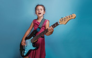 Kız Avrupa görünüm on yıl gitar çalmak bir blu üzerinde şarkı söylüyor.