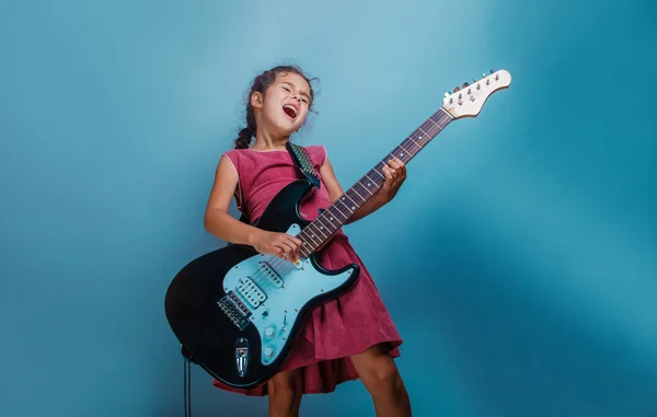 Ragazza aspetto europeo dieci anni a suonare la chitarra su un bac blu — Foto Stock