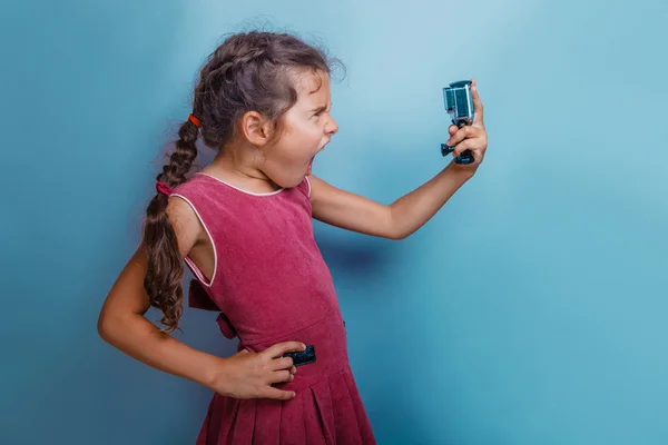 Girl child holding a camera in his hand shooter opened her mouth — Stock Photo, Image