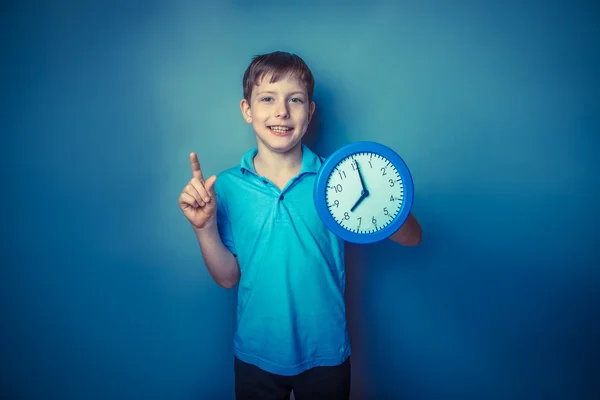 Niño adolescente europeo apariencia diez años celebración de un reloj de pared — Foto de Stock