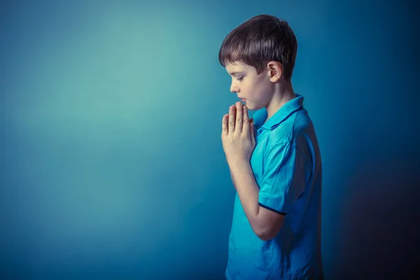 Boy teenager European appearance ten years stands sideways prayi — Stock Photo, Image