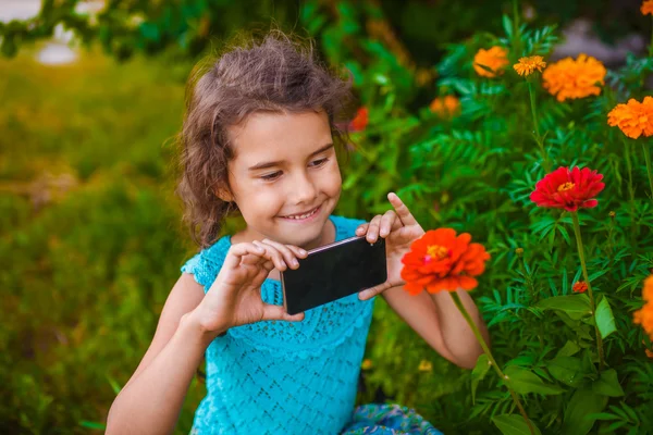 Teen girl child photographed flower on the outside phone nature — Stockfoto