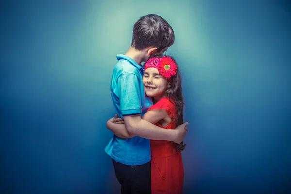 Teenager Mädchen umarmt einen Teenager Jungen auf einem grauen Hintergrund retro pho — Stockfoto