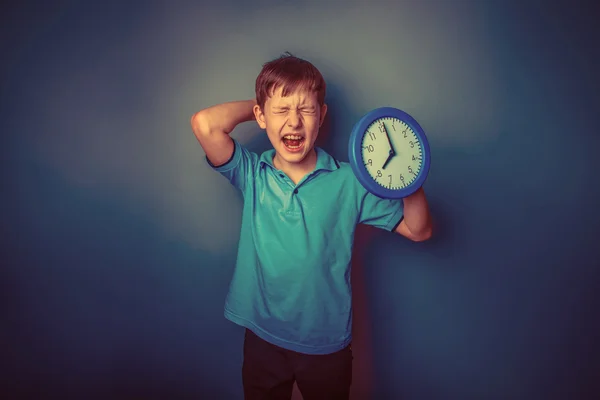Niño adolescente europeo apariencia diez años celebración de pared reloj op — Foto de Stock
