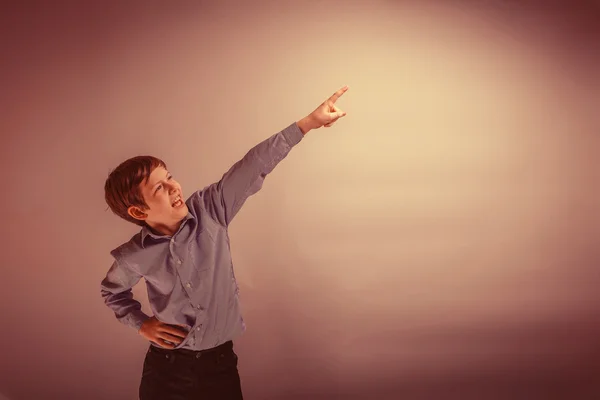 Boy teenager of European appearance indicates his hand up on a g — Stock Photo, Image