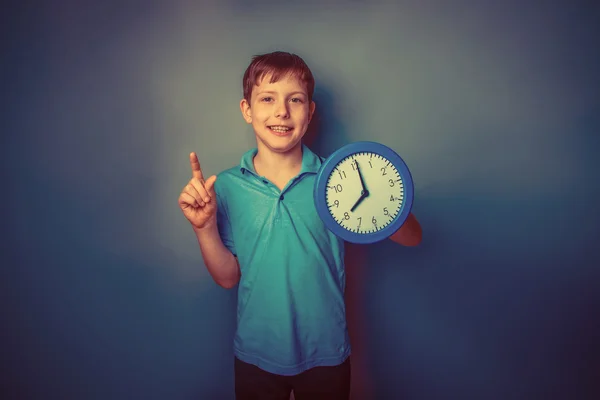 Ragazzo adolescente aspetto europeo dieci anni in possesso di un orologio da parete — Foto Stock