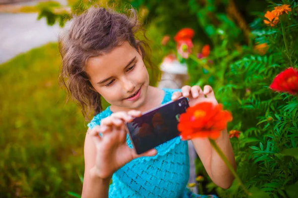 Teenage girl photographing flower phone on a green background in — Stock Photo, Image