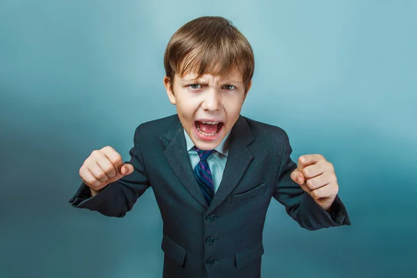 A boy of twelve European appearance in a suit shouting angry  on — Stock Photo, Image