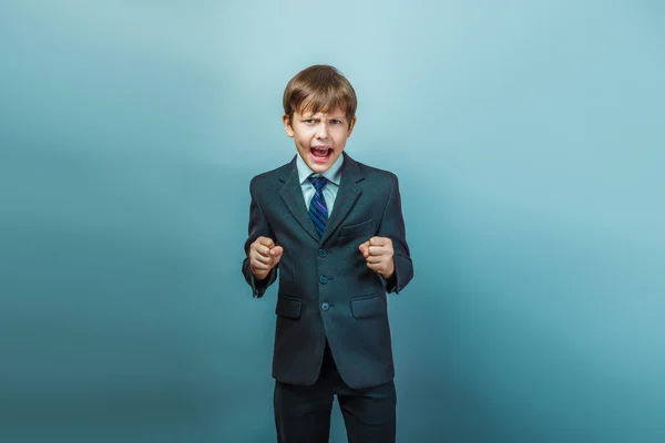 A boy of twelve European appearance in a suit shouting angry on — Stock Photo, Image