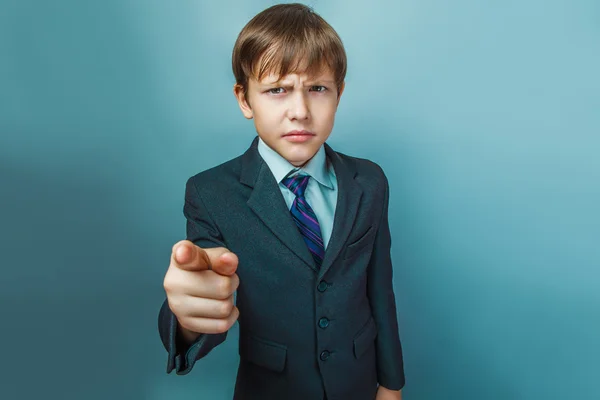 A boy of twelve European appearance in a suit shows a finger at — 图库照片