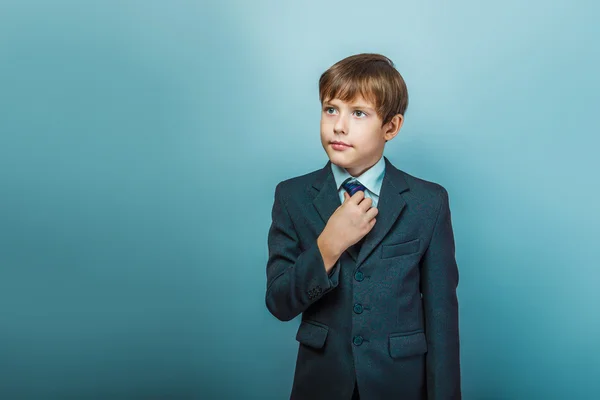 A boy of twelve European appearance in a suit straightens his ti — 图库照片