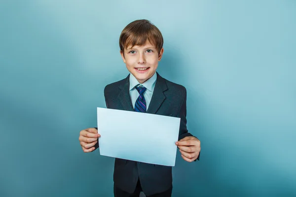 A boy of twelve European appearance in a suit holding a blank sh — Stock Photo, Image