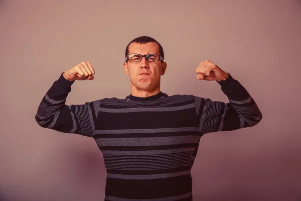 European-looking man of 30 years in glasses shows muscles retro — Stok fotoğraf