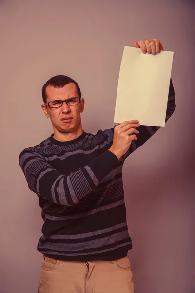 Un homme d'allure européenne de 30 ans tenant une feuille blanche, en ressentiment — Photo