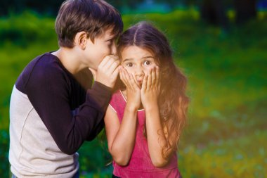 girl whispering in the ear of the boy tells the secret hearings  clipart