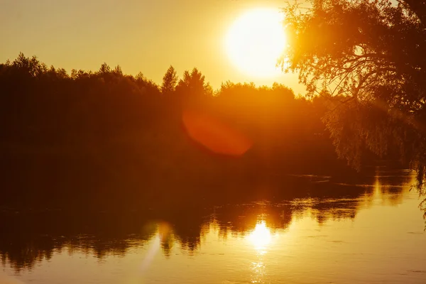 Kvällen solnedgång på floden sun sätter orange ljus silhuetter na — Stockfoto