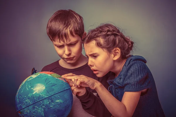 Teenage boy with a girl looking at a globe showing thumbs up on — Stock Photo, Image