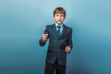 a boy of twelve European appearance in a suit shows his fists on
