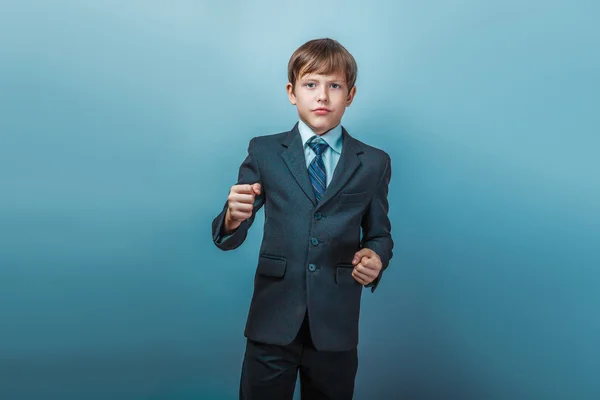 Un niño de doce años de apariencia europea en un traje muestra sus puños en — Foto de Stock