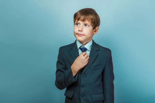 Um menino de doze europeu aparência em um terno endireita seu ti — Fotografia de Stock