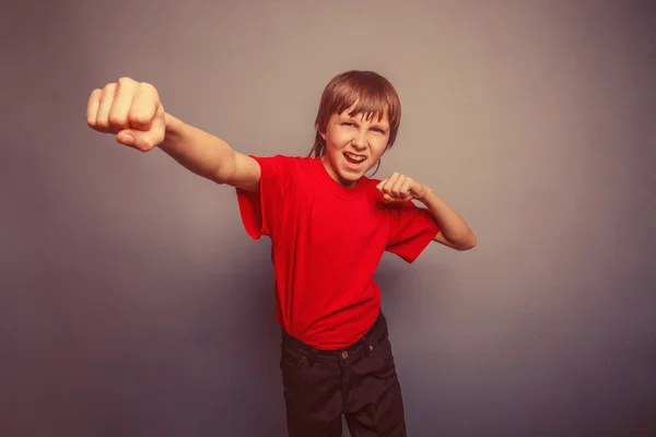 Boy, teenager, twelve his years  red  in shirt, fists  red showi — Stock Photo, Image