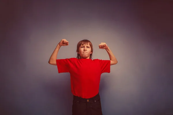 Chlapce, teenagera, dvanáct let v červené košili, ukazuje sílu v — Stock fotografie