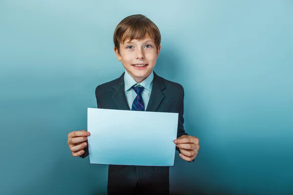 A boy of twelve European appearance in a suit holding a blank sh — Stock Photo, Image