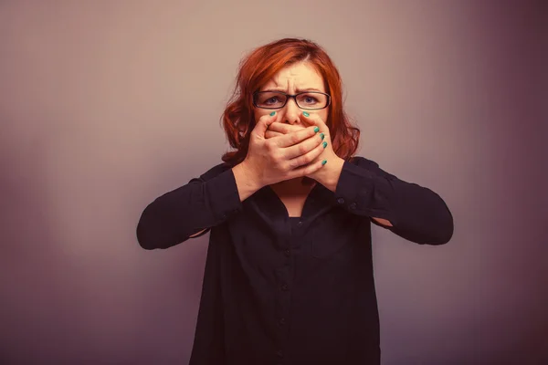 European appearance redheaded girl in glasses covering her mouth — Stok fotoğraf