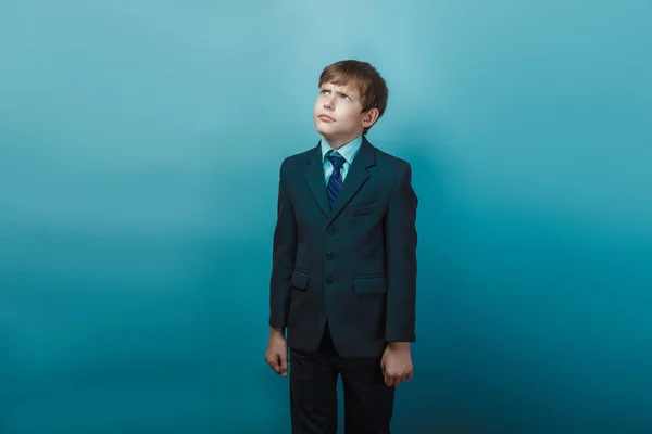 A boy of twelve European appearance in a suit looking up frowns — Stockfoto