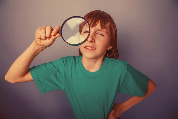 European-looking boy of ten years a joke, looking through a magn — Stock Photo, Image