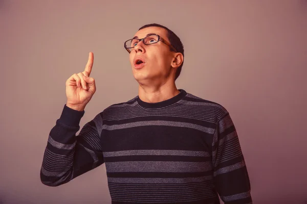 Male of European appearance brunet showing thumb up on a gray ba — Stock Photo, Image