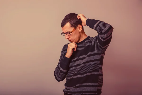 Male of European appearance brunet thinking on a gray background — Stock Photo, Image