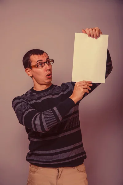 Evropská vypadající muž 30 let drží prázdný list, překvapení — Stock fotografie