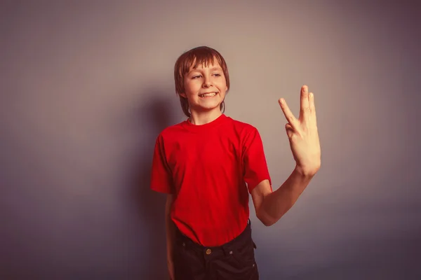 Menino adolescente Europeu aparência em uma camisa vermelha mostrando polegares d — Fotografia de Stock